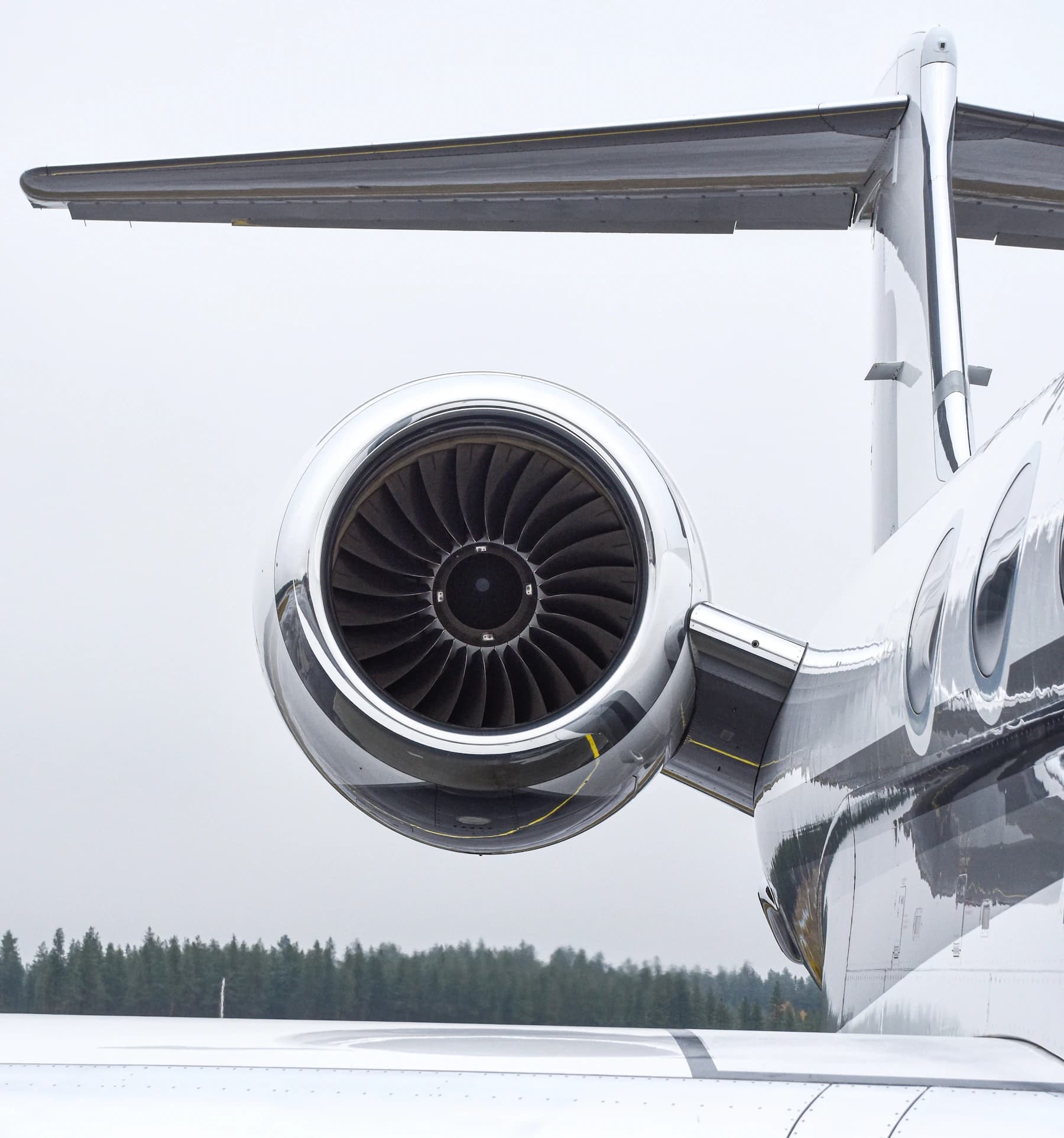 Close-up of a private jet engine, wing and fuselage on an airport tarmac