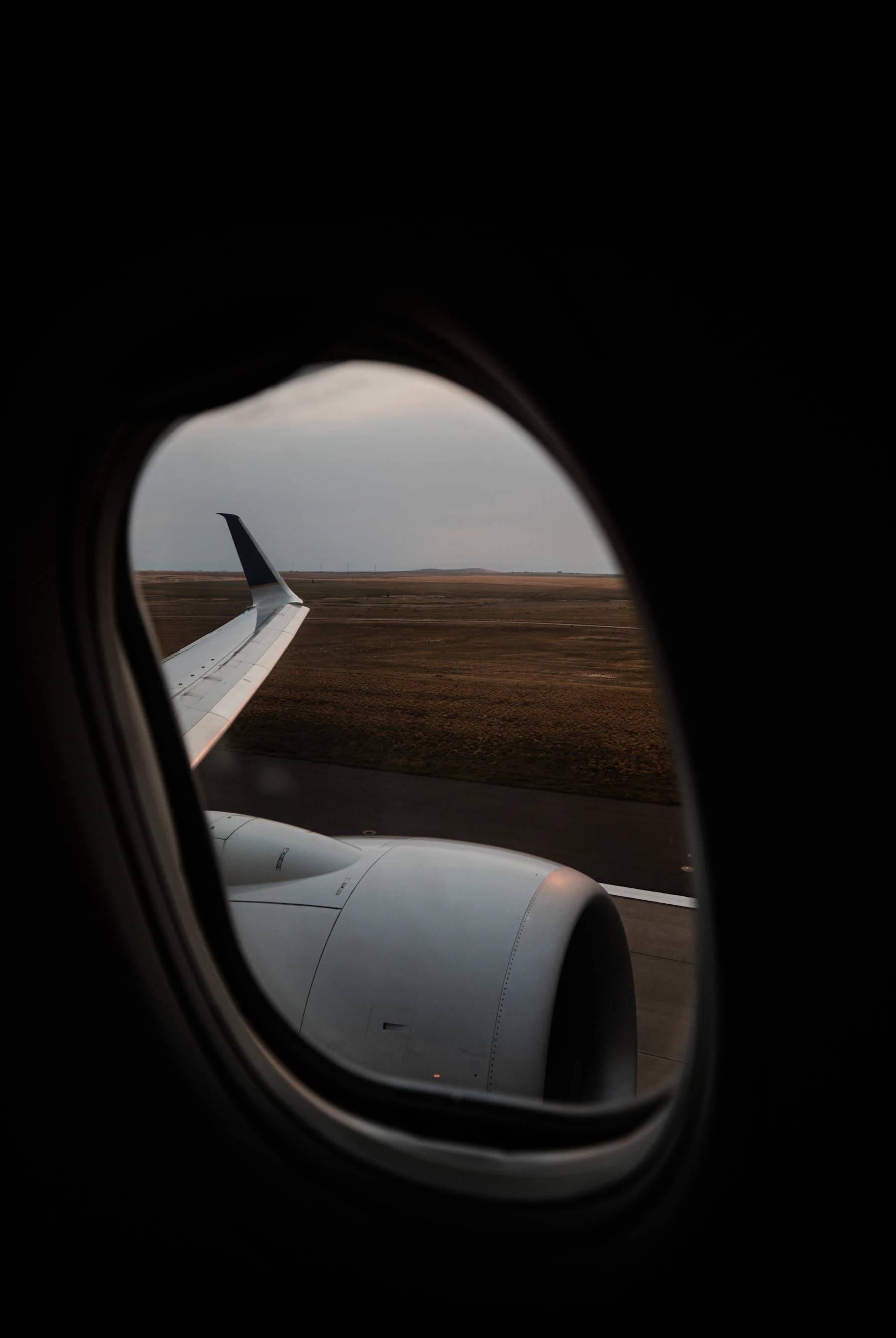 Aircraft wing and engine viewed through a cabin window