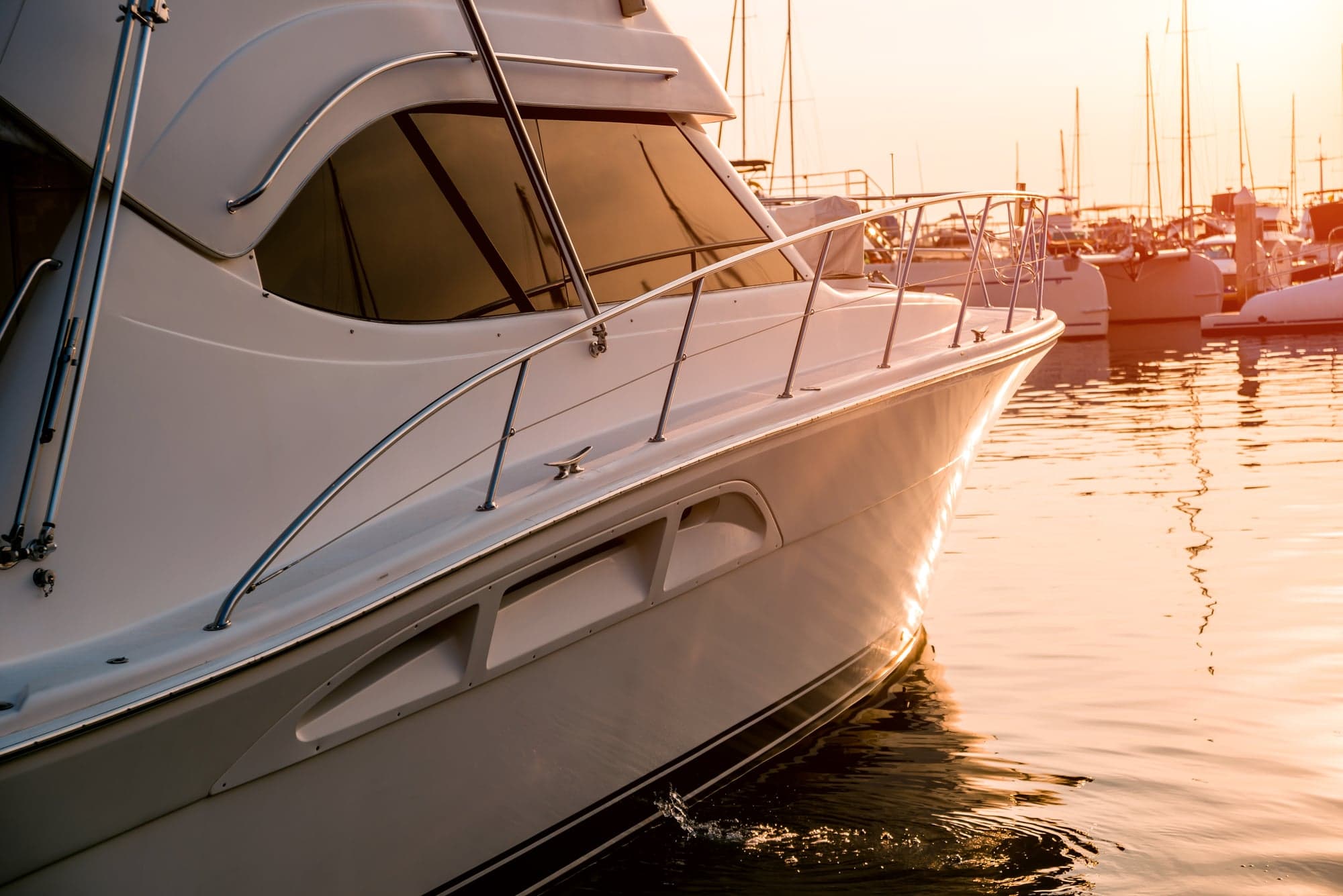 White motor yacht moored in calm marina water at sunset
